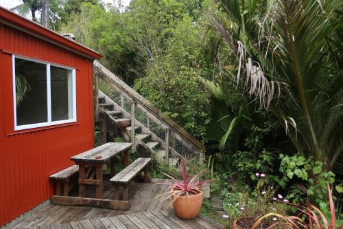 a wooden deck with a bench next to a red building at Te Nikau Retreat in Punakaiki