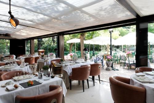 a restaurant with white tables and chairs and windows at CAZAUDEHORE Hôtel Restaurant Gastronomique Terrasse et Jardins in Saint-Germain-en-Laye