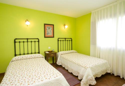 two beds in a room with green walls at Hotel Rural Suquin in Navia