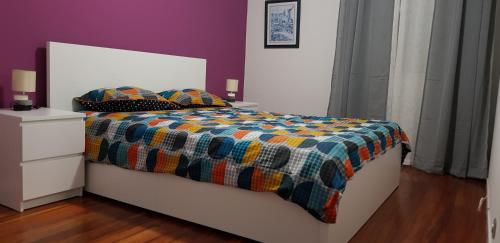 a bed with a colorful comforter and two pillows on it at Varanda do Atlântico in Ponta Delgada