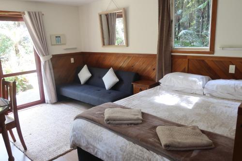 a bedroom with a bed and a couch in it at Te Nikau Retreat in Punakaiki