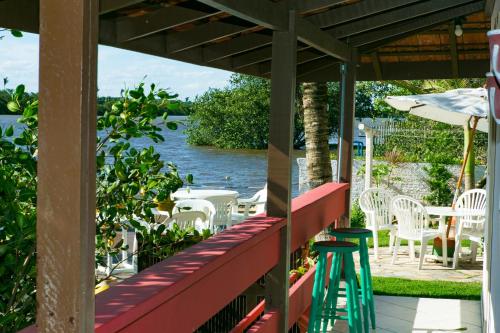 een veranda met stoelen en tafels en uitzicht op het water bij Pousada Kanaxuê in Barra Velha