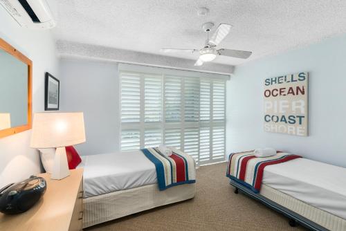 a bedroom with two beds and a desk and a window at Solnamara Beachfront Apartments in Gold Coast