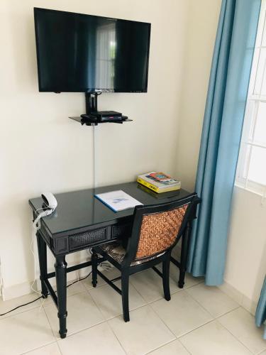 a black desk with a chair and a television at Turtle Ridge Apartments in Saint James