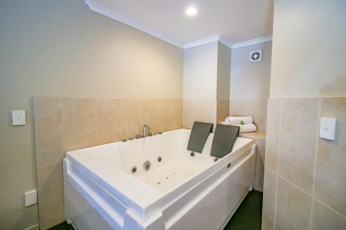 a large white tub in a bathroom with tiles at Aotea Motor Lodge in Whanganui