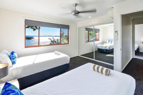 a bedroom with two beds and a mirror at Hamilton Island Holiday Homes in Hamilton Island