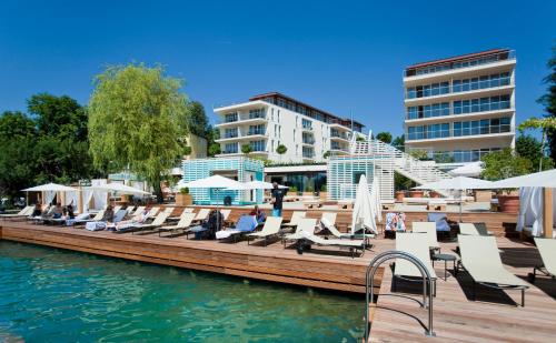 a dock with lounge chairs on the water at Lake's - My Lake Hotel in Pörtschach am Wörthersee