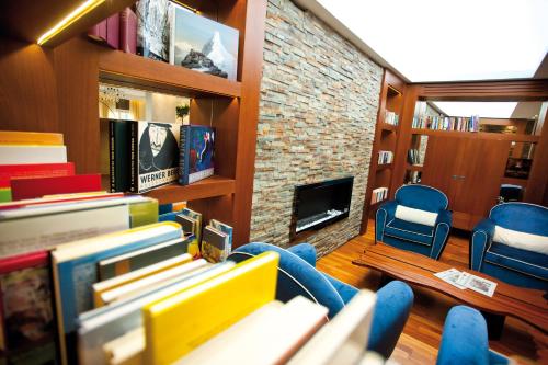 a living room with a stack of books and a fireplace at Lake's - My Lake Hotel in Pörtschach am Wörthersee