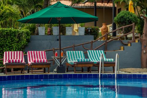 three chairs and an umbrella next to a swimming pool at Hotel Panorama in Unawatuna