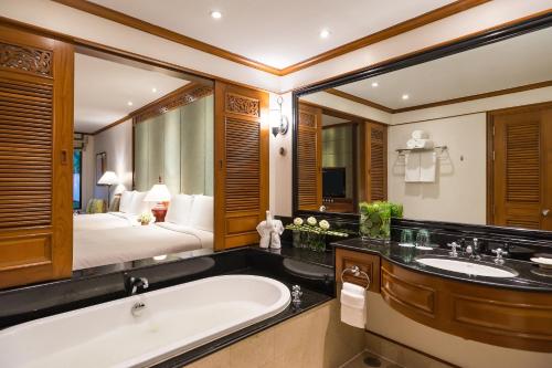 a bathroom with a tub and a bed in a room at JW Marriott Phuket Resort and Spa in Mai Khao Beach