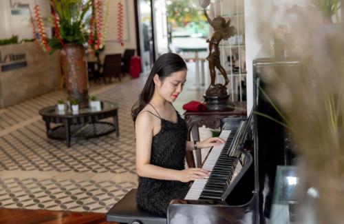 a young girl playing a piano in a store at Le House Boutique Hotel - 100m to the beach in Da Nang