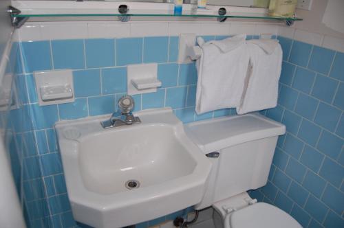 La salle de bains est pourvue de carrelage bleu, d'un lavabo et de toilettes. dans l'établissement Sea Breeze Ocean City, à Ocean City