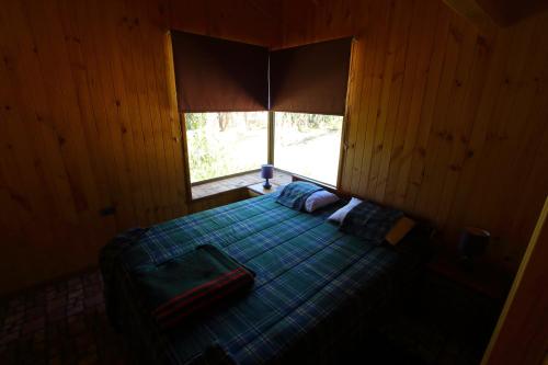 1 dormitorio con 1 cama y ventana grande en Cabaña Vintage, en Algarrobo