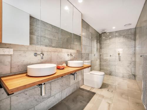 a bathroom with two sinks and a toilet at Tamarama Apartments in Sydney
