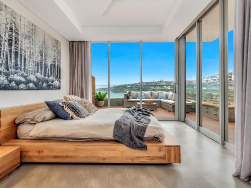 a bedroom with a bed and large glass windows at Tamarama Apartments in Sydney