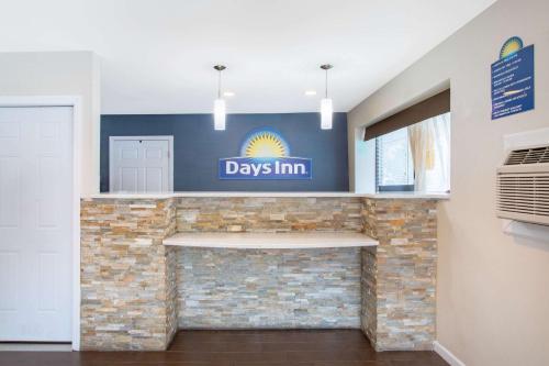 a lobby with a day inn sign on a brick fireplace at Days Inn by Wyndham Elmsford in Elmsford
