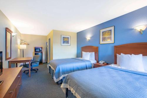 a hotel room with two beds and a desk at Days Inn by Wyndham Elmsford in Elmsford