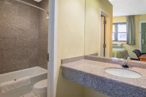 a bathroom with a sink and a toilet and a mirror at Days Inn by Wyndham Elmsford in Elmsford