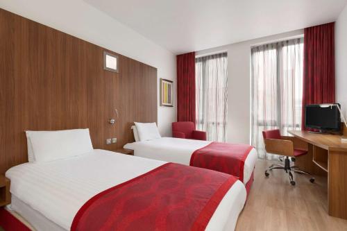 a hotel room with two beds and a desk at Ramada Encore Leicester City Centre in Leicester