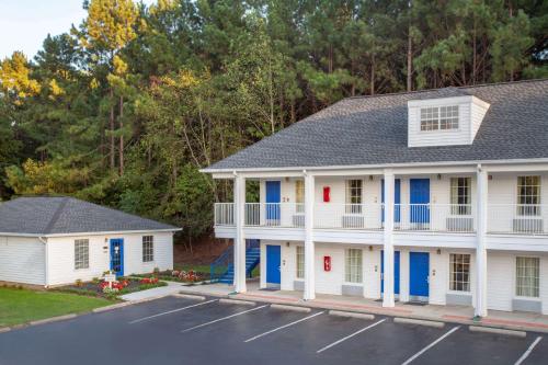 a white house with blue doors and a parking lot at Baymont by Wyndham Greenwood in Greenwood