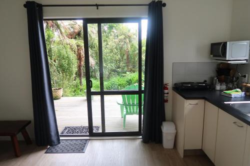 a kitchen with a door open to a patio at Te Nikau Retreat in Punakaiki