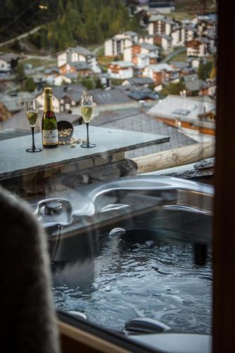 a tub with two glasses of wine and a bottle of champagne at Boutique Lodge Spycher in Saas-Fee
