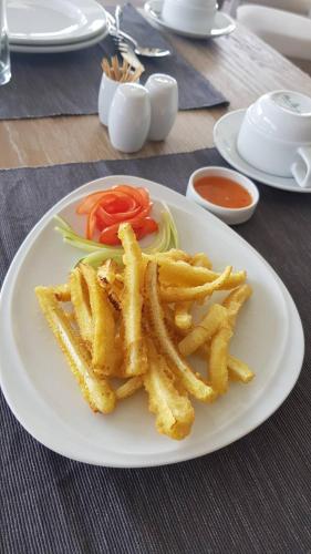 a white plate with french fries and tomatoes on a table at VST Residence -SHA PLUS Certified in Ban Khlong Bang Ping