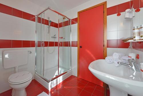 a red and white bathroom with a toilet and a sink at Hotel Maisonnette in Torgnon