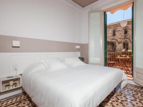 a white bedroom with a large bed and a balcony at Ecozentric in Barcelona