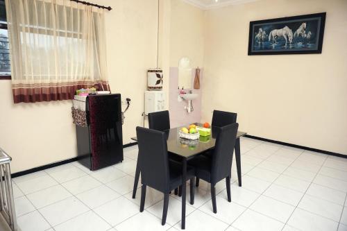 uma sala de jantar com uma mesa e cadeiras e um frigorífico em Villa Cemara em Batu