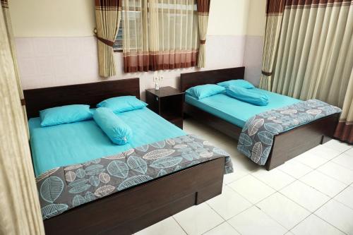 Duas camas com almofadas azuis num quarto em Villa Cemara em Batu