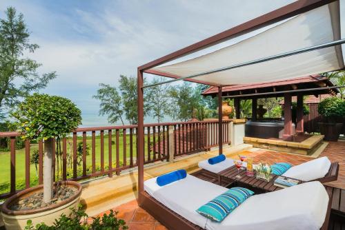 a patio with a white couch and chairs on a deck at JW Marriott Phuket Resort and Spa in Mai Khao Beach
