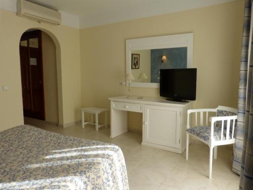 a bedroom with a bed and a desk with a television at Gran Sol in Zahara de los Atunes