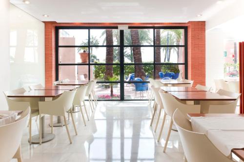 un restaurant avec des tables et des chaises et une grande fenêtre dans l'établissement Hotel El Palmeral, à Benidorm