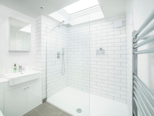 a white bathroom with a shower and a sink at Teviot Cottage in Corbridge