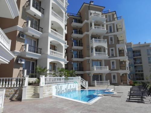 un gran edificio de apartamentos con piscina frente a él en Antorini Apartments en Sveti Vlas