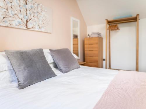 a bedroom with a white bed with two gray pillows at Teviot Cottage in Corbridge