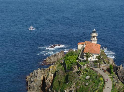 a lighthouse on a cliff next to the ocean at Hotel Rural Suquin in Navia