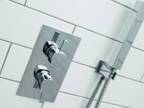 a shower head on a white tile wall at Teviot Cottage in Corbridge