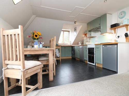 a kitchen with green cabinets and a table and chairs at The Watch in Porthcurno