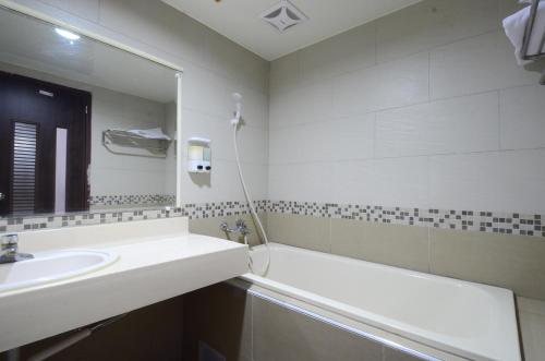 een badkamer met een wastafel, een bad en een spiegel bij Galaxy Hotel in Zhongli