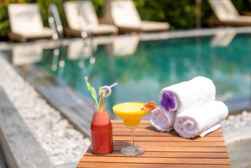 a table with a drink and towels next to a swimming pool at The Son Villa Hoi An in Hoi An