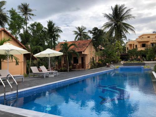 a swimming pool with chairs and umbrellas next to a house at Thai Tan Tien Hotel in Phu Quoc