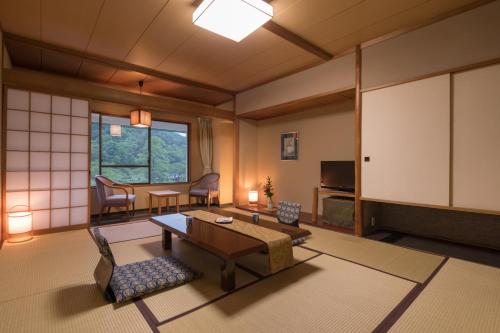 Hotel Hanamaki في هاناماكي: غرفة معيشة مع غرفة كبيرة مع طاولة وكراسي