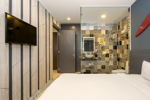 a bedroom with a bed and a tv on a wall at Le House Boutique Hotel - 100m to the beach in Da Nang