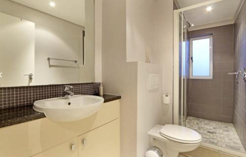 a white bathroom with a sink and a toilet at Portico 606 in Bloubergstrand