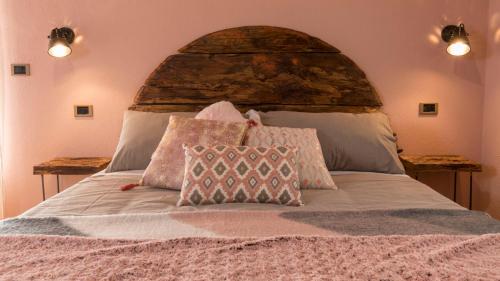 a bed with a large headboard with two pillows on it at Le Jasmin in Aosta