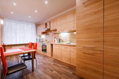 une cuisine avec des placards en bois et une table avec des chaises dans l'établissement ANNA Riga Apartment, à Riga