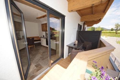 an open balcony with sliding glass doors and a kitchen at Kaiserappartements-Marie in Ellmau