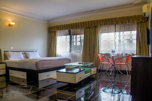 um quarto com uma cama, uma mesa e cadeiras em Alfa Hotel Munyonyo em Kampala